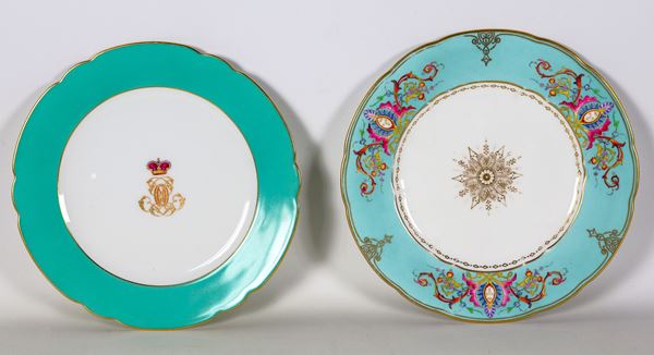 Lotto di due antichi piatti da muro in porcellana Parigi e in porcellana Copeland, decorati e variopinti a motivi di volute floreali e stemma con corona