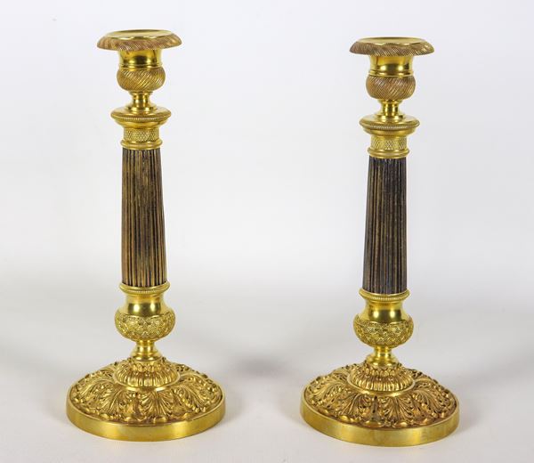Pair of antique French Empire candlesticks in gilded, patinated, chiselled and embossed bronze, shafts in the shape of neoclassical columns.