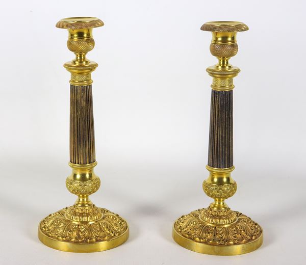 Coppia di antichi candelieri francesi Impero in bronzo dorato, patinato, cesellato e sbalzato, fusti a forma di colonne neoclassiche.