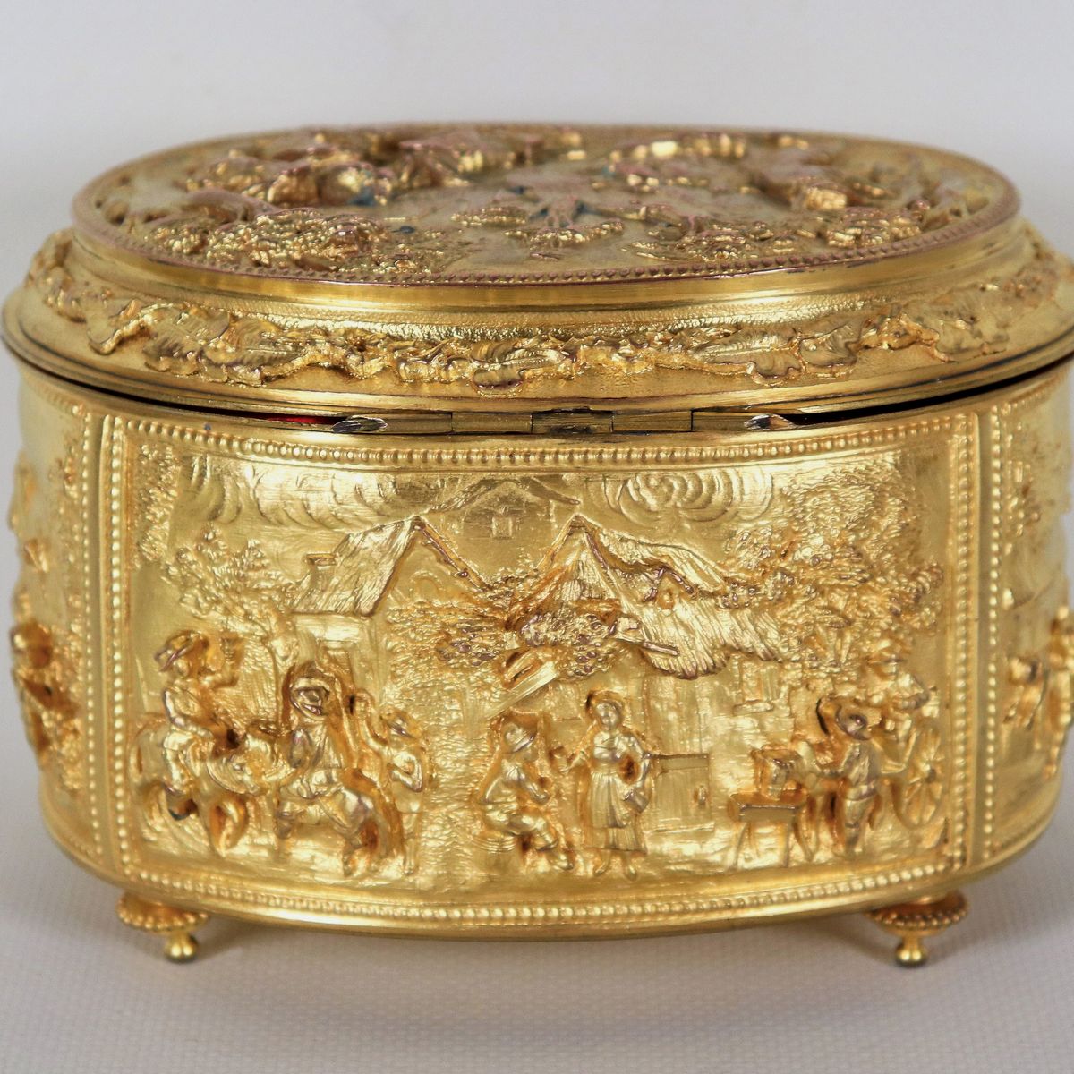 Antica scatola francese ovale in bronzo dorato, interamente cesellata e sbalzata a motivi di paes...