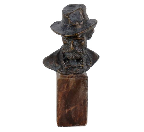 Alceo Dossena - Firmato. "Uomo con cappello", piccolo busto in bronzo sorretto da basetta in marmo danneggiata