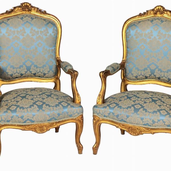 Coppia di poltrone romane di linea Luigi XV, in legno dorato e intagliato a motivi di foglie d'acanto e conchiglie, braccioli e gambe ricurve. Copertura in tessuto damascato