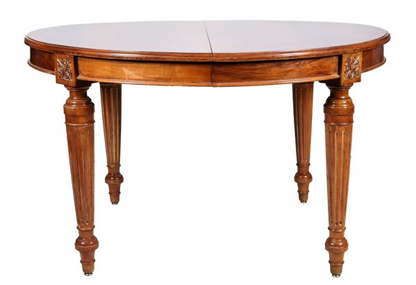 Antico tavolo da pranzo francese di linea Luigi XVI in mogano chiaro, a forma ovale allungabile con tre prolunghe non originali, quattro gambe a cono scannellato