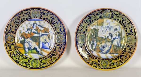 Coppia di piatti da parata in maiolica lustrata Gualdo Tadino, marcati Luca della Robbia, interamente decorati e variopinti con al centro scene dell'antica Roma "Ottaviano visita Cleopatra" e "Nerone decide di darsi la morte"