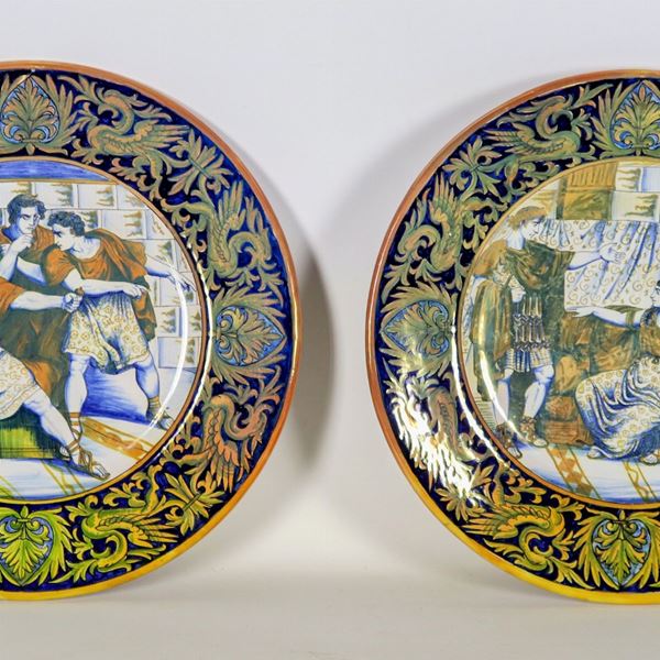 Coppia di piatti da parata in maiolica lustrata Gualdo Tadino, marcati Luca della Robbia, interamente decorati e variopinti con al centro scene dell'antica Roma "Ottaviano visita Cleopatra" e "Nerone decide di darsi la morte"