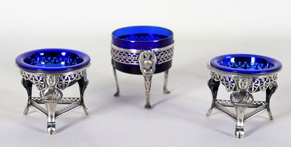 Lot of three French Empire era salt shakers in silver, chiselled and embossed with neoclassical motifs with cobalt blue crystal trays, two form a pair, gr. 138