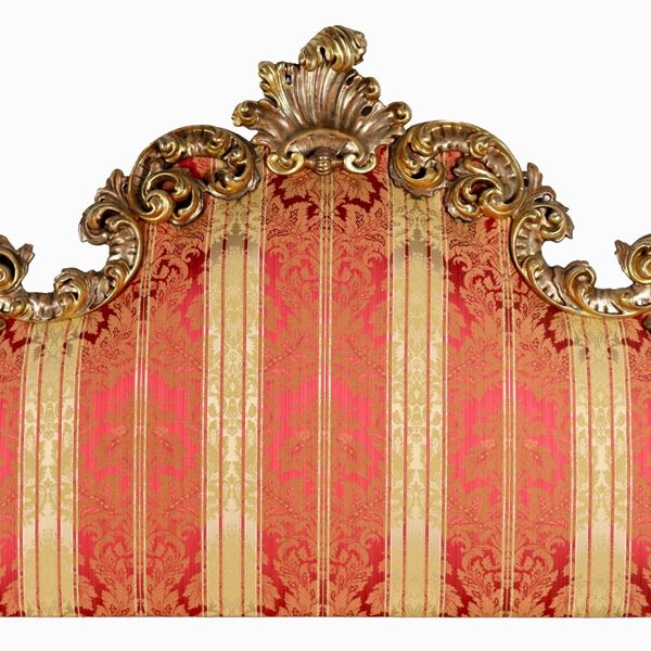 Testata da letto con elementi antichi in legno dorato a mecca e intagliato a motivi di ricci, foglie d'acanto e conchiglia centrale, copertura in tessuto fiorato