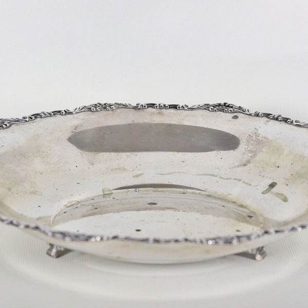 Fruttiera tonda in argento con bordo cesellato e sbalzato, sorretta da tre piedini ricurvi, gr. 320
