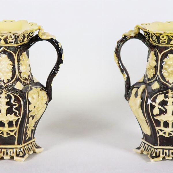 Coppia di antichi piccoli vasi in porcellana nera, con decorazioni chiare a rilievo a motivi di cineserie. I colli dei vasi sono restaurati e lievemente difettati