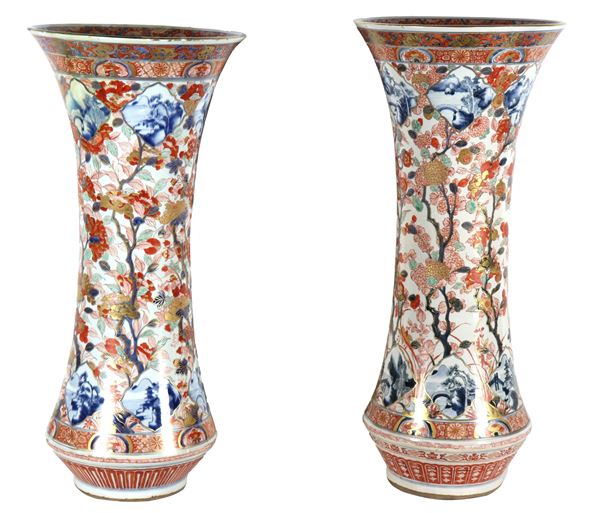 Coppia di antichi grandi vasi giapponesi a tromba in porcellana Imari, con decorazioni in smalti policromi a rilievo di fiori esotici e rami. Un vaso presenta vecchio restauro al collo 