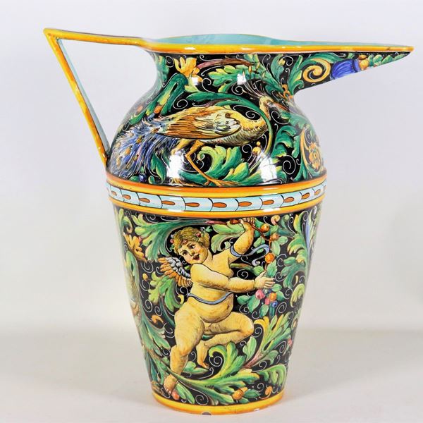Grande brocca in maiolica lustrata Gualdo Tadino firmata Alfredo Santarelli (1874-1957), interamente decorata con putti, fiori e uccelli. Lieve filatura interna al becco