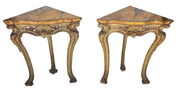 Coppia di consolles ad angolo di linea Luigi XV, in legno laccato, dorato e intagliato, tre gambe ricurve e piani decorati a finto marmo