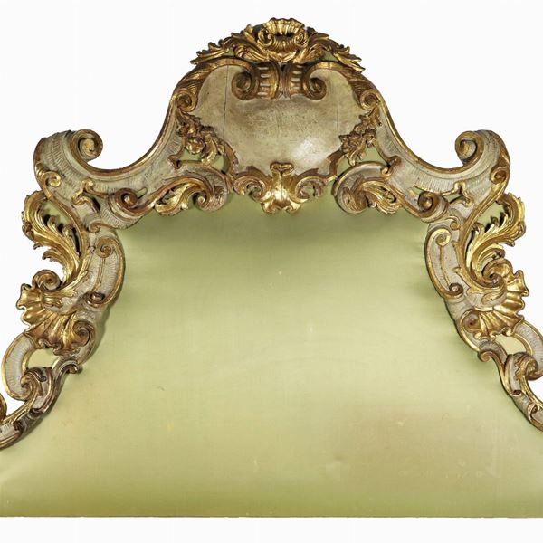 Testata da letto di linea Luigi XV in legno dorato e laccato verde, con intagli a motivi di volute, foglie d'acanto, ricci, conchiglie e fiori