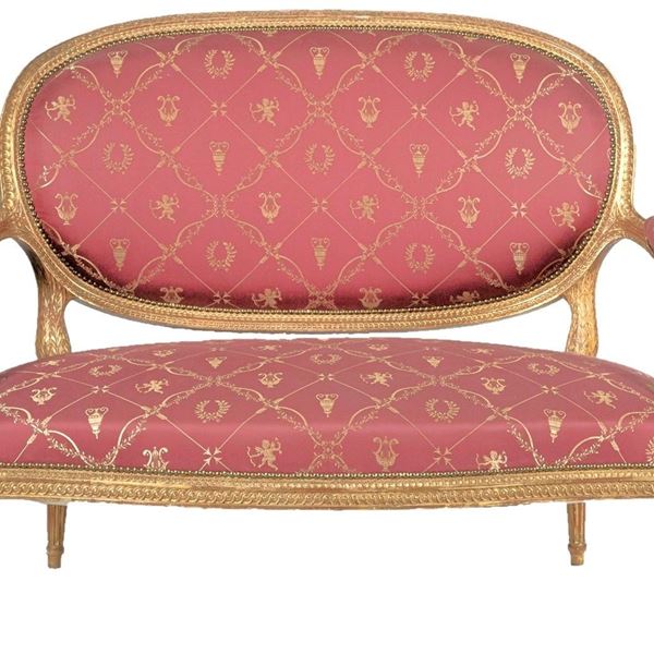 Antico piccolo divano francese di linea Luigi XVI, in legno dorato e intagliato a motivi neoclassici, copertura in tessuto rosso porpora a disegni di amorini, anfore e ghirlande di alloro. Il tessuto è usurato