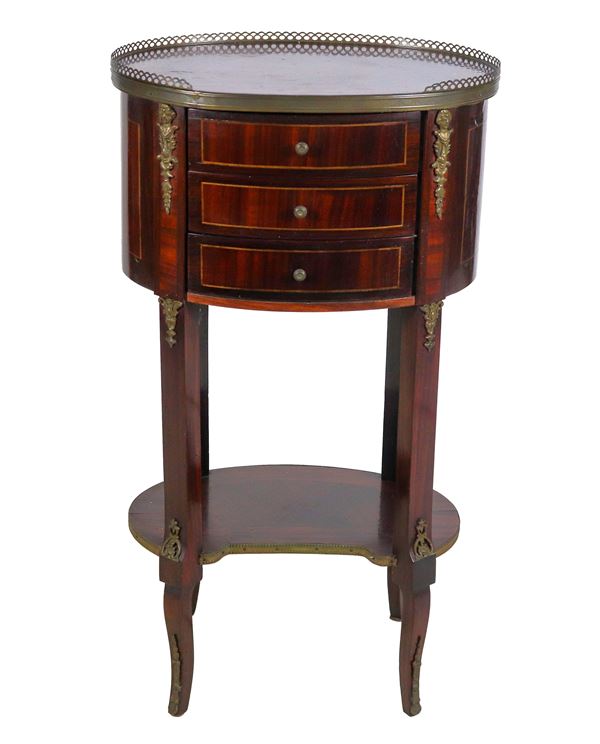 Oval-shaped French gueridon in mahogany, with marqueterie inlays, three drawers and four legs joined by a shelf below
