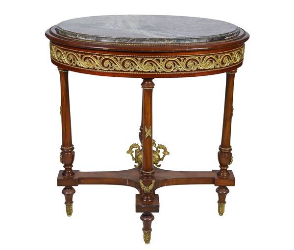 French oval center table from the Impero line in mahogany, with friezes and trimmings in gilded bronze, embossed and chiseled with neoclassical motifs, four column legs joined by a cross surmounted by a bronze amphora and top in green breccia marble