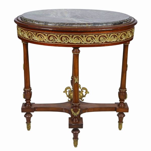 French oval center table from the Impero line in mahogany, with friezes and trimmings in gilded bronze, embossed and chiseled with neoclassical motifs, four column legs joined by a cross surmounted by a bronze amphora and top in green breccia marble