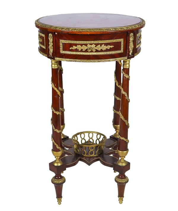 French center table with a round shape of the Empire line, in purple ebony and mahogany, with gilded and chiseled bronze trimmings and friezes with neoclassical motifs, a central drawer and four column legs joined by a cross surmounted by a bronze basket