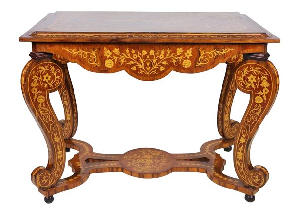 Rectangular center table in walnut, entirely inlaid in satin wood with motifs of garlands and floral scrolls, four curved legs joined by a shaped cross