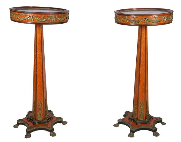 Pair of French trestle center tables, in thuja briar and bois de rose, with friezes and trimmings in gilded and chiseled bronze with neoclassical motifs, round-shaped tops supported by faceted columns resting on shaped bases