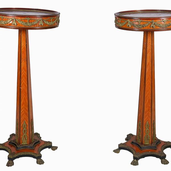 Coppia di tavolini francesi da centro a trespolo, in radica di tuja e bois de rose, con fregi e guarnizioni in bronzo dorato e cesellato a motivi neoclassici, piani a forma tonda sorretti da colonne sfaccettate poggianti su basi sagomate