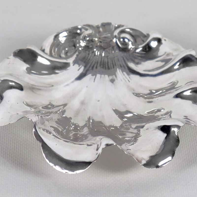 Portabonbon a forma di conchiglia in argento cesellato e sbalzato, sorretto da quattro piedini, g...
