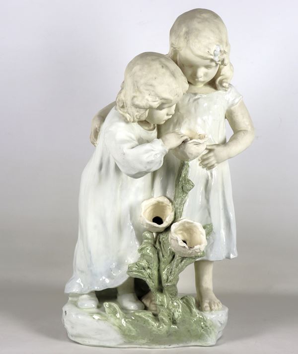 "Bambine con fiori", gruppo in ceramica e porcellana morbida smaltata, firmato Augmuller Ludwig (1876-?), modellista e scultore del Periodo Art Nouveau. Lieve mancanza