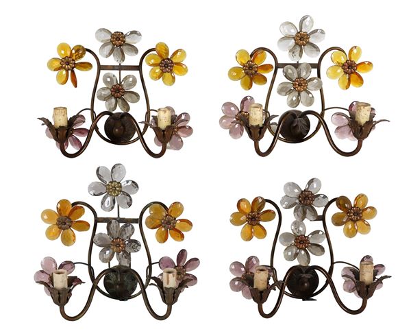 Lot of four Liberty wall sconces in bronzed metal, with applications of amber-colored crystal flowers and petals, two lights each. Slight defects and some lacks in the petals