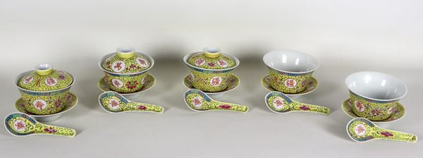 Lotto di cinque ciotole cinesi in porcellana con piattini e cucchiai, con decorazioni a rilievo in smalti policromi su fondo giallo a motivi orientali. Tre con coperchio e due senza