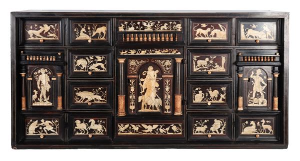 Ancient Tuscan coin cabinet in ebony and ivory, with panels inlaid with motifs of mythological figures and hunting scenes, in the center a small temple-shaped door with eight pullers inside and a series of pullers on the sides. Late 17th century. The lot is accompanied by a CITES certificate