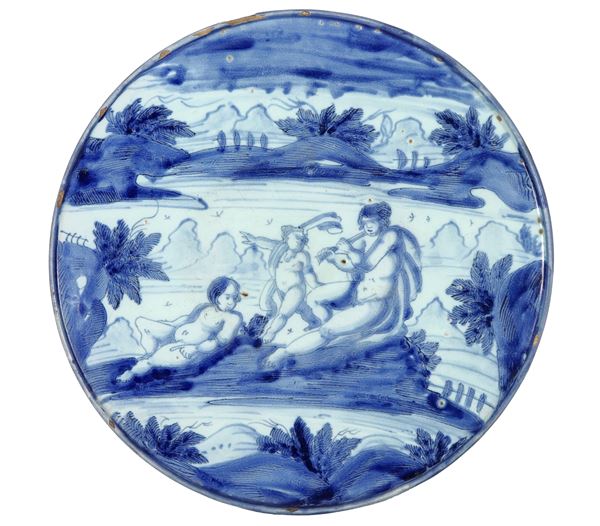 Antico sottocoppa in maiolica ligure con decorazione in blu a motivo di figure mitologiche, qualche mancanza al bordo