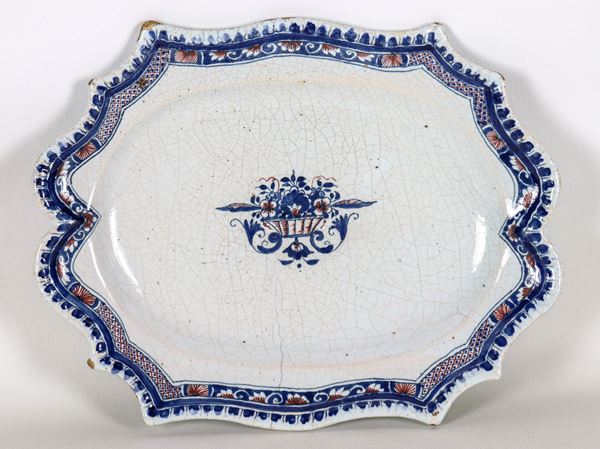 Ancient oval curved majolica plate with decorated edge and vase with flowers in the centre, defects with cracking and slight losses