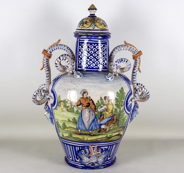 Grande anfora in maiolica Italia Meridionale con scena variopinta a motivo contadino, manici a forma di serpenti. Qualche mancanza e coperchio restaurato