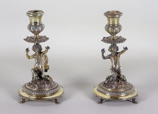 Coppia di piccoli candelieri in argento cesellato e sbalzato con sculture di Tritoni e conchiglie,  gr. 930
