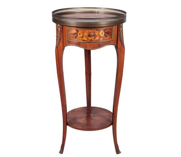 Round-shaped French gueridon in bois de rose and purple ebony with floral motif inlays, top with perforated railing, central drawer and four curved legs joined by a shelf below