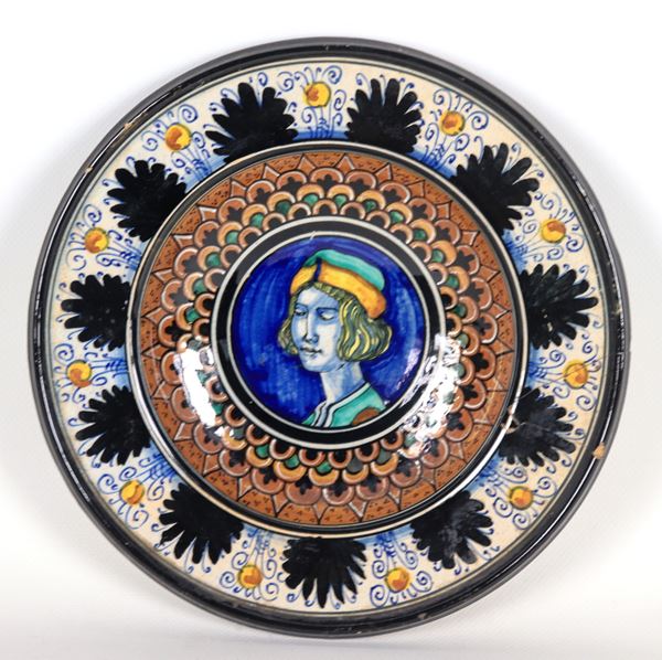 Piatto da muro in maiolica di Pesaro marcato M.A.P.(Maiolica Artistica Pesarese 1930 - 1940), interamente decorato in blu, marrone e verde, al centro "Nobiluomo con cappello". Sul bordo rottura incollata