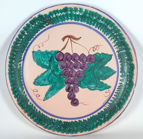 Large Neapolitan majolica wall plate with green decorations, a bunch of grapes in the centre