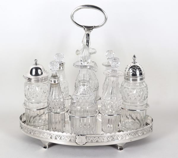 Ancient English cruet in silver from the George III period, with pierced edge and supported by four curved feet, six ampoules and two worked crystal bottles. Dublin stamps, late 17th century