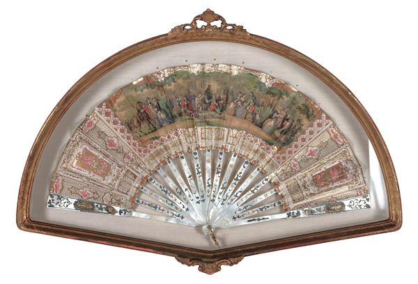 Antique mother-of-pearl fan with printed and colored party scene between nobles, gilded wood noticeboard frame
