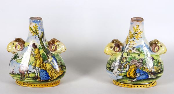 Pair of small majolica flasks from Pesaro, entirely colorful with "Shepherds with flocks" and "Landscapes" motifs, handles in the shape of goats' heads