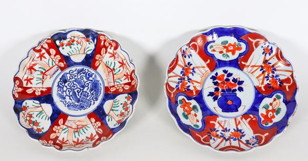 Coppia di antichi piatti giapponesi in porcellana Imari, con decorazioni variopinte a motivi di fiori e foglie orientali, bordi centinati 