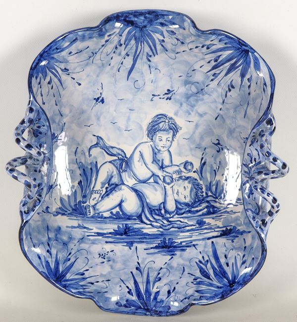 Centrotavola in maiolica di Albisola, interamente decorato in blu con figure di putti e fogliame, bordo frastagliato