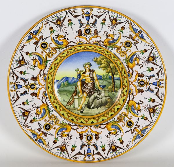 Piatto da parata in maiolica lustrata di Faenza marcato Minardi (Fratelli Minardi Ceramiche Faentine), interamente decorato sul bordo con al centro paesaggio con Bacco. Anni '20-'30