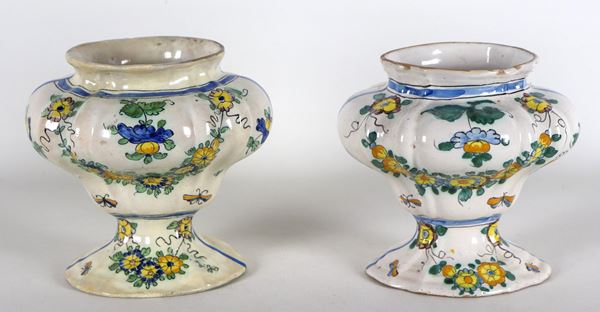 Coppia di vasi in maiolica italiana con decorazioni policrome di ghirlande floreali. Un vaso presenta diversi vecchi restauri