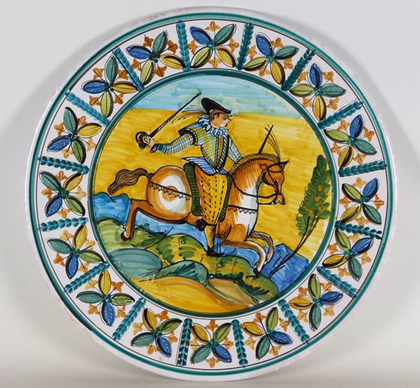 Grande piatto da parata in maiolica, interamente decorato sui bordi e figura di cavaliere con spada al centro, marcato La Bottega-Ceramiche Artistiche Giuseppe Indino Lucugnano (LE)