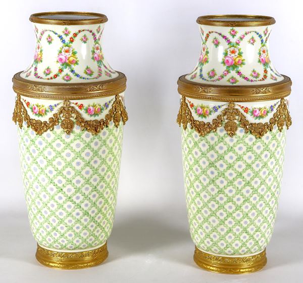 Coppia di vasi in porcellana di Sevres, con decorazioni policrome a motivi floreali e geometrici, guarnizioni e fregi in bronzo dorato e cesellato