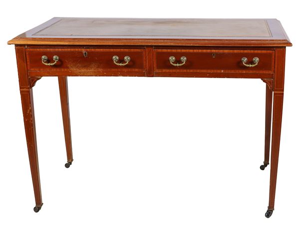 Antico tavolo scrittoio in mogano Epoca Regina Vittoria, con filettature intarsiate in legno satinato, due tiretti, piano in pelle e quattro gambe a tronco di piramide rovesciata. Lievi difetti