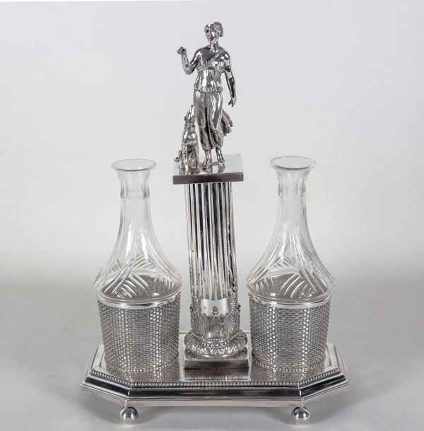 Antica oliera in argento cesellato e sbalzato a motivi neoclassici con scultura di Venere e cane, due ampolle in cristallo mancanti dei tappi, una con lieve sbeccatura al bordo del collo. Bolli Italia Inizio XIX Secolo, gr. 840