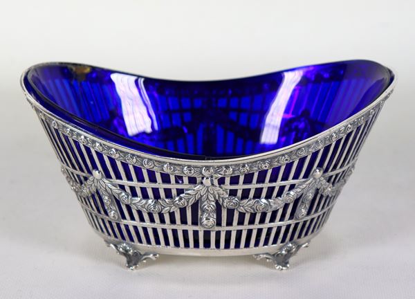 Cestino ovale in argento interamente cesellato, sbalzato e traforato a motivi Luigi XVI, sorretto da quattro piedini ricurvi. All'interno vaschetta in cristallo blu cobalto danneggiata, gr. 350