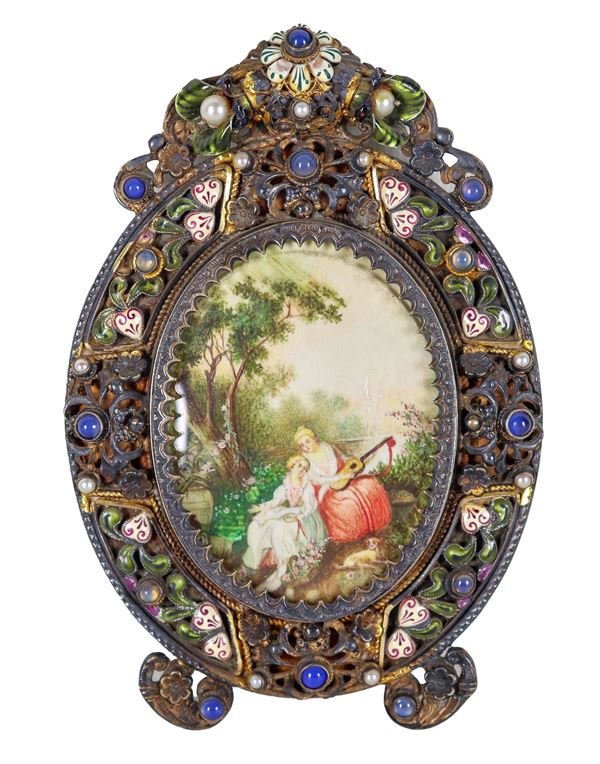 Antica miniatura ovale dipinta con scena bucolica, in cornice in bronzo cesellato e sbalzato con applicazioni di smalti, pietre dure e perle